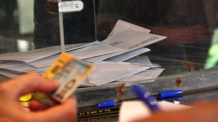Foto d'arxiu d'una urna i una mà que comprova el DNI per poder votar. Agència Catalana de Notícies