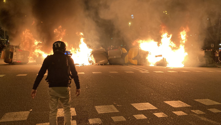 Un manifestant davant d'una barricada de contenidors encesa en la quarta nit de protestes per l'empresonament de Pablo Hasel. Barcelona, 19 febrer del 2021. Agència Catalana de Notícies