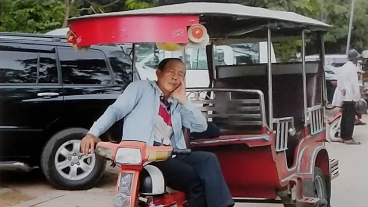 Taxista, descansant amb una mà al manillar, al Vietnam. Eva Murgui