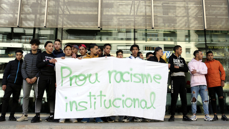 Joves que viuen al centre d'acollida de Sant Gregori, darrere una pancarta on s'hi pot llegir 'Prou racisme institucional'. Agència Catalana de Notícies