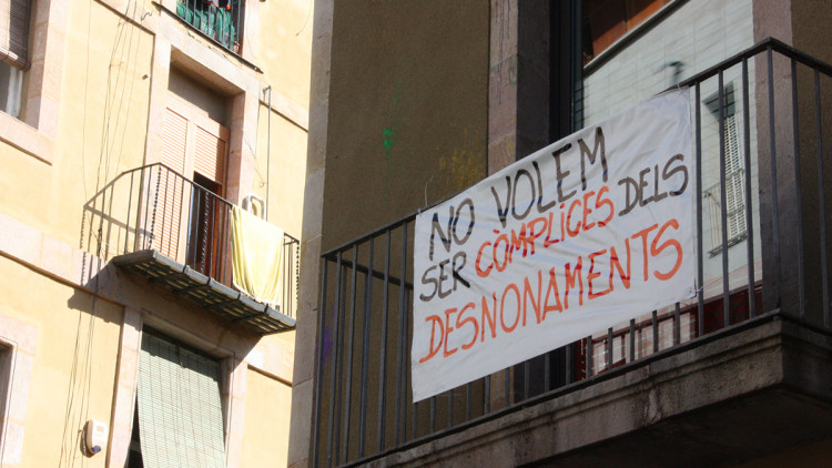 Pla mitjà d'una pancarta col·locada al balcó del Centre de Serveis Socials del Raval on s'hi llegeix "No volem ser còmplices dels desnonaments", en motiu de la vaga organitzada pels treballadors del centre. Imatge del 28 de maig de 2021. Agència Catalana de Notícies
