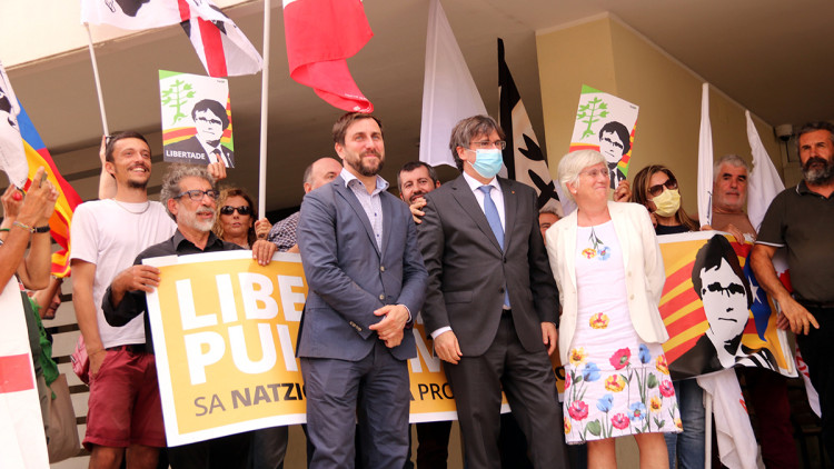Puigdemont, Comín i Ponsatí a la sortida del tribunal de Sàsser i davant una pancarta de suport, el 4 d'octubre del 2021. Agència Catalana de Notícies