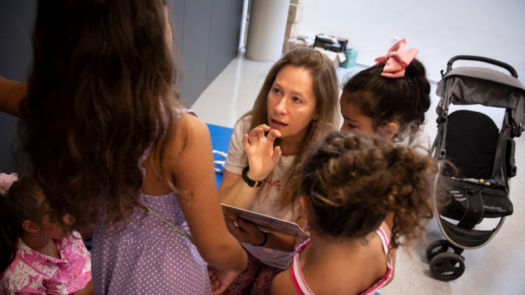 Mercè Ortíz, educadora de la biblioteca de Bon Pastor, atén unes criatures mentre les mares assisteixen a un programa d’inserció laboral que es fa a la biblioteca.