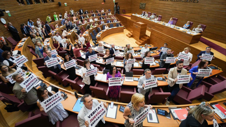 Els parlamentaris socialistes, amb pancartes a les mans, i els de Compromís, amb llibres, protesten contra lʼaprovació de la llei de concòrdia davant els diputats de Vox, exultants.. Europa Press