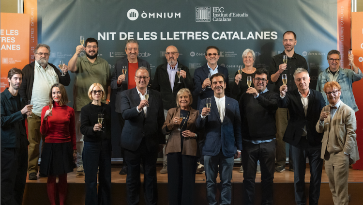 Al centre, Xavier Antich, president d'Òmnium, i Teresa Cabré, presidenta de l'IEC. Darrere seu els representants dels grups Penguin Random House (Joan Riambau), Abacus Futur (Jaume Roures) i Grup 62 (Emili Rosales), acompanyats de representants de la Diputació de Barcelona, l'Associació Dramàtica, els gremis d'editors i de llibreters, l'Associació d'Editors, la Institució de les Lletres Catalanes i 3 cat.
