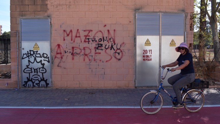 Una veïna circula amb bicicleta per Paiporta davant una pintada contra Carlos Mazón.. Víctor Maceda
