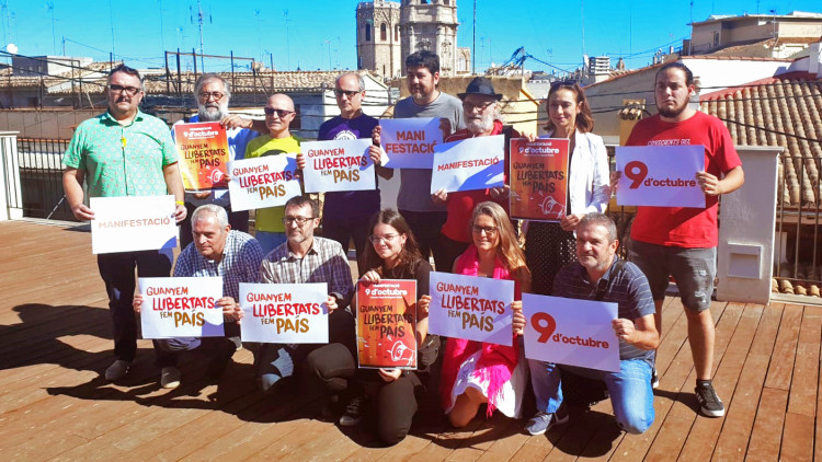 Els diferents integrants dels col·lectius que integren la Comissió 9 d'Octubre amb el lema de la manifestació durant la diada valenciana| ACPV