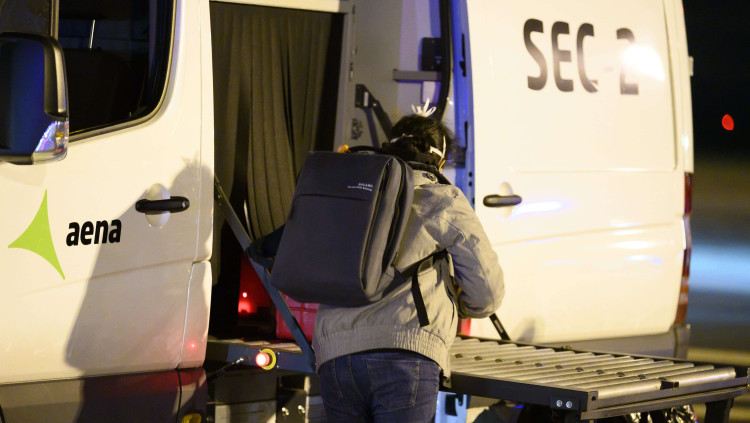 Una dona repatriada de la ciutat xinesa de Wuhan pel risc de coronavirus carrega maletes en un autobús abans de ser traslladada a l'hospital. Agència Catalana de Notícies