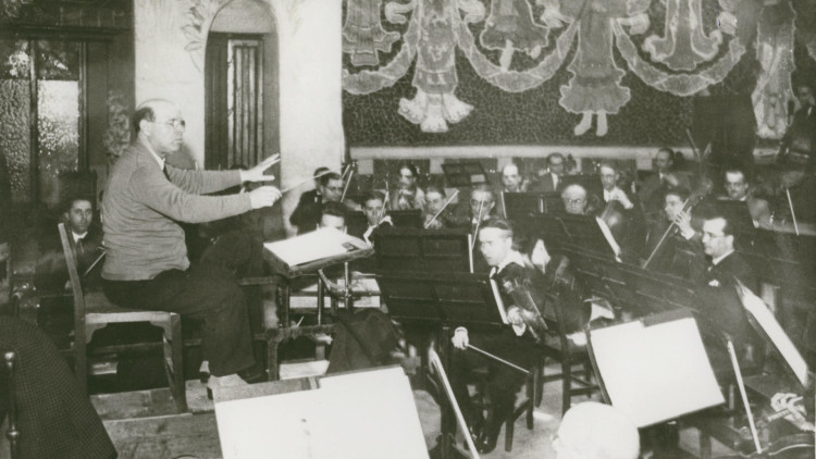 Pau Casals davant la seva orquestra durant un assaig al Palau de la Música Catalana. ©Centre de Documentació de l’Orfeó Català (CEDOC)