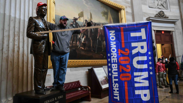 Un simpatitzant de Donald Trump es fotografia al costat de l’estàtua a Gerarld R. Ford que es troba als passadissos del Capitoli.. Europa Press